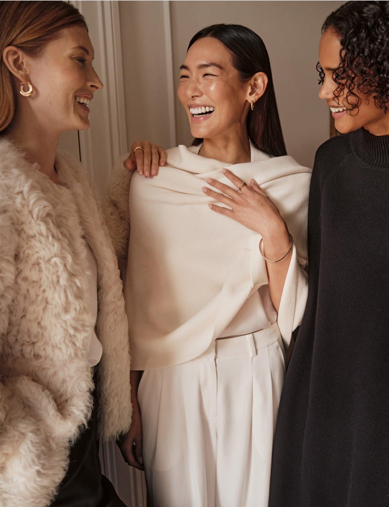 a woman in a white sweater and pants sitting on a stool